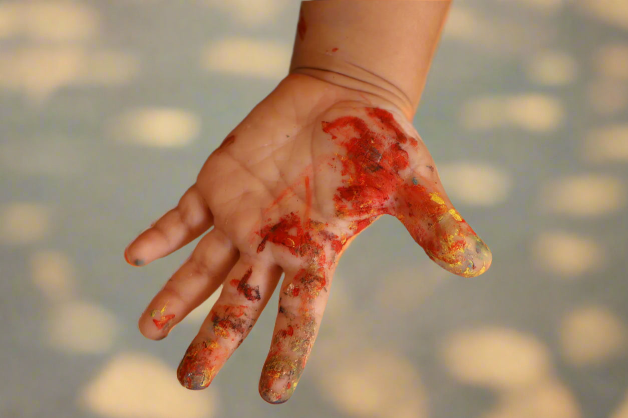 Hand with red paint stains on a sandy background
